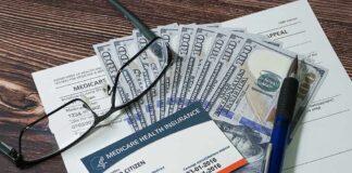 Medicare card on paperwork with cash, glasses, and a pen