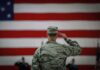 Soldier saluting before a large American flag