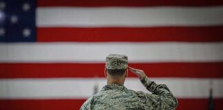 Soldier saluting before a large American flag
