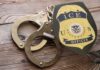ICE officer badge and handcuffs on wooden surface