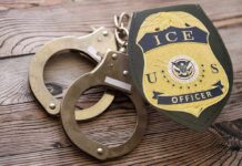 ICE officer badge and handcuffs on wooden surface
