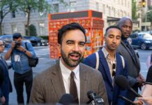 Zohran Mamdani speaking to reporters on a city sidewalk