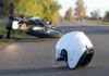 White motorcycle helmet on road with fallen bike in background